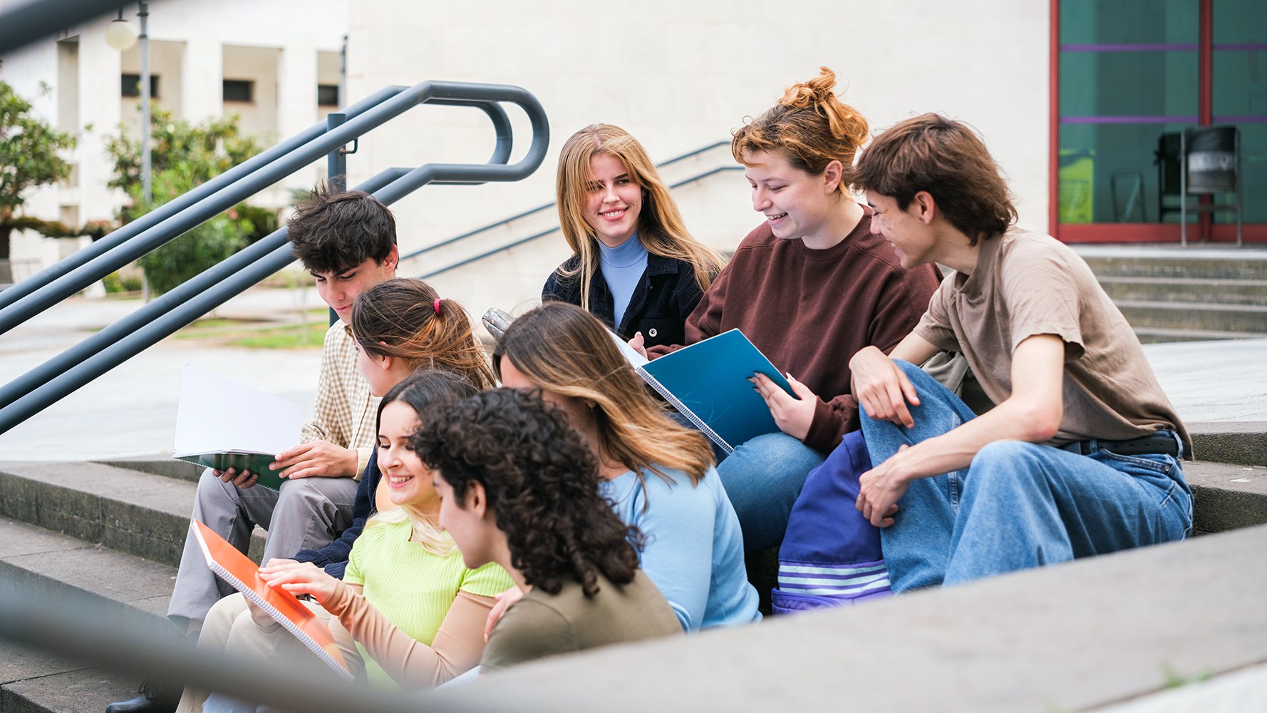 Austauschstudentinnen und -studenten sitzen auf einer Treppe und unterhalten sich