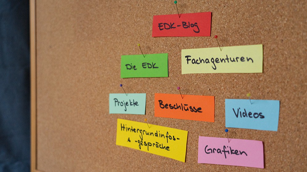 Eine Korkpinnwand mit farbigen Zetteln, auf denen «EDK-Blog», «Fachagenturen»,«Projekte», «Beschlüsse», «Die EDK», «Hintergrundinfos & -gespräche», «Videos» und «Grafiken» steht