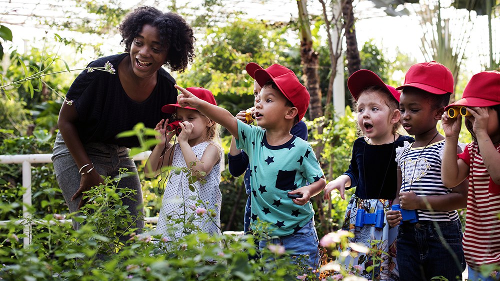 Eine Lehrerin zeigt einigen Kindern einen Garen