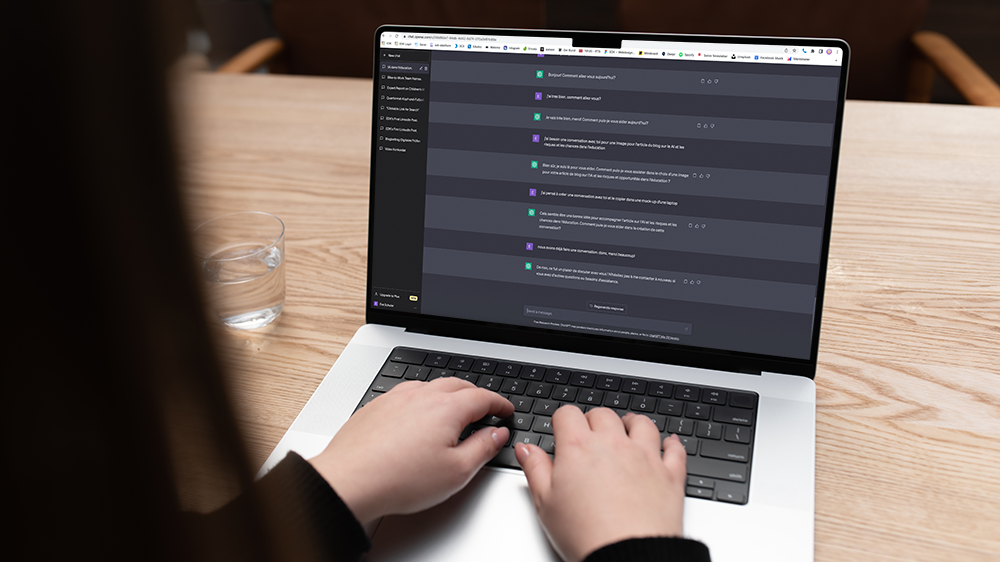 Blick über die Schulter einer Frau auf einen Laptop, auf dem ein Chat mit ChatGPT zu sehen ist