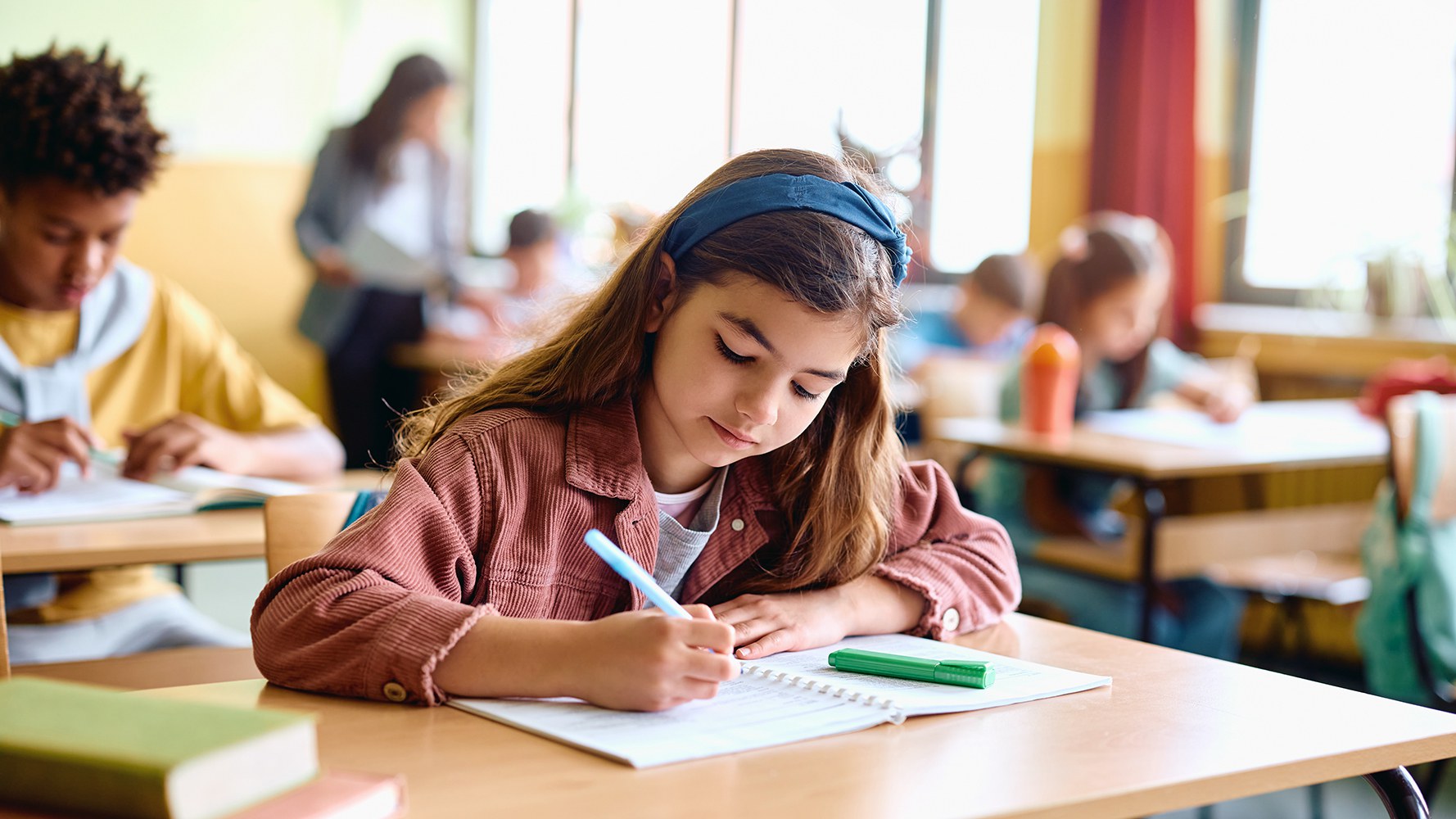 Ein Mädchen schreibt in der Schule etwas in ein Heft