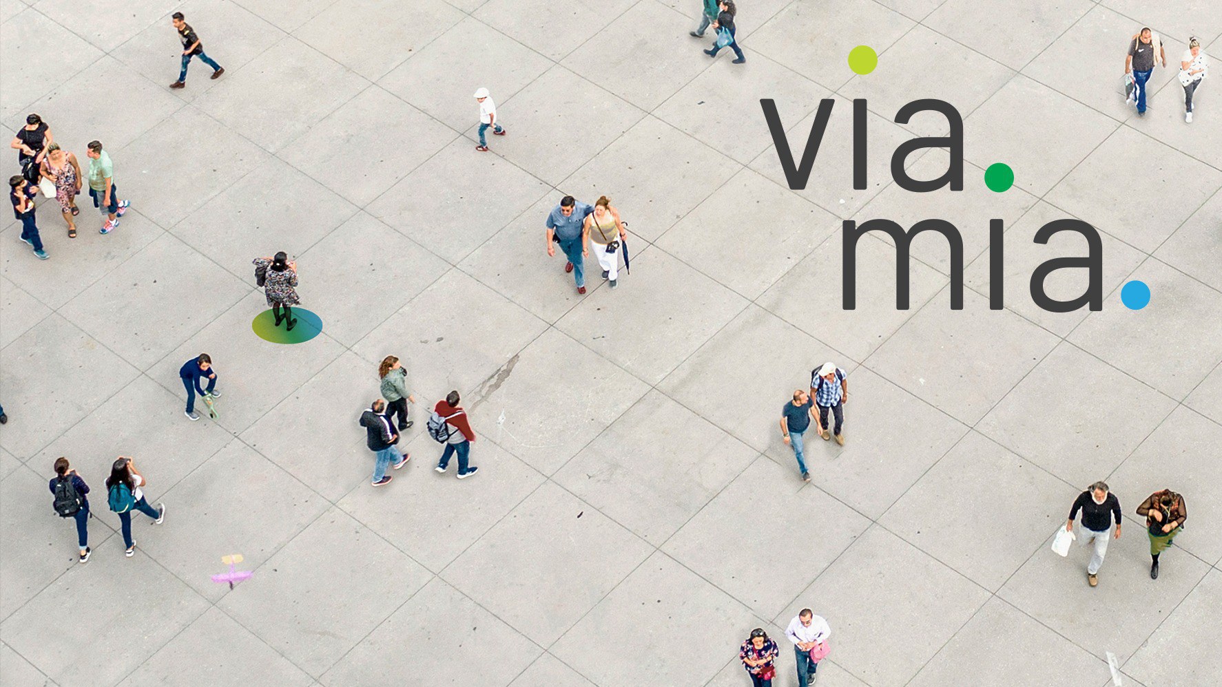 Une place vue d’en haut, sur laquelle se promènent des personnes; en haut à droite figure le logo de viamia