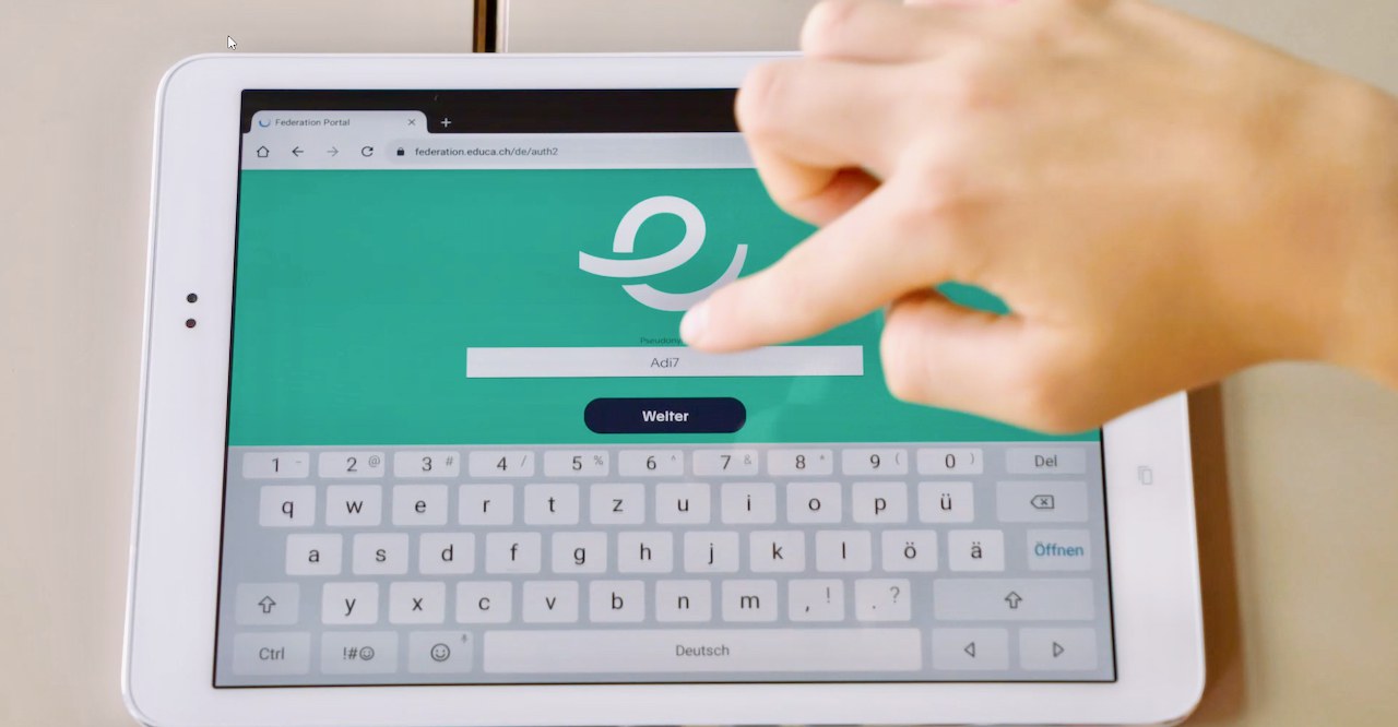 Une Tablette est posée sur la table, la page de connexion d’Edulog est visible à l’écran.