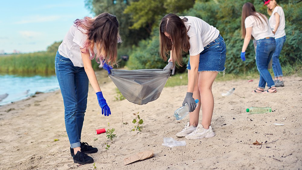 Jugendliche sammeln Abfall an einem Sandstrand am See